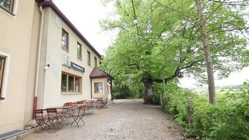 Gasthaus Weinberg. Älteres Gebäude mit Biergarten und Bäumen.