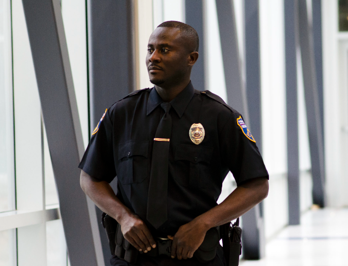 A man in a police uniform is standing in a hallway