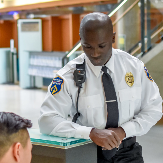 A man in a security uniform is talking to another man