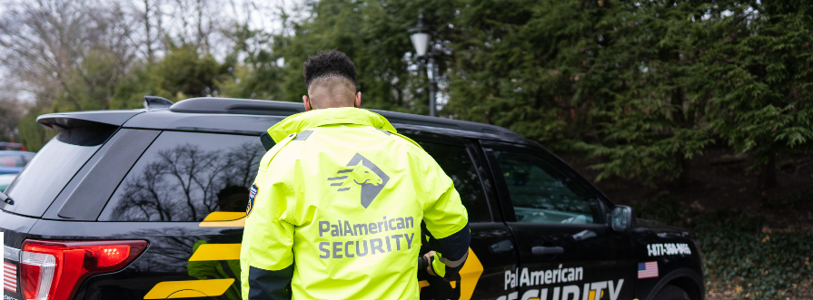 A man in a yellow jacket is standing in front of a black suv.