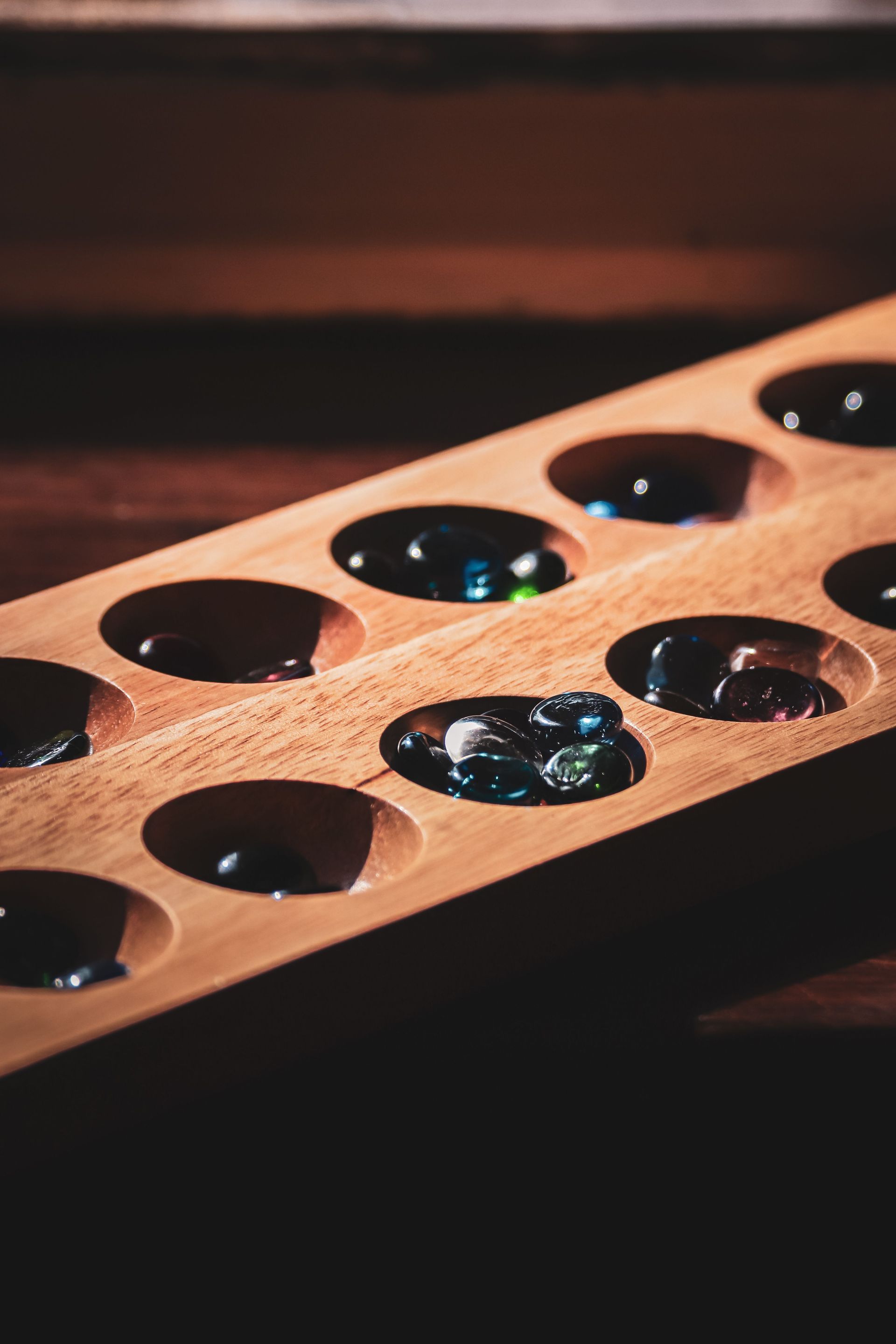 Vassoio di legno contenente biglie nere lucide con riflessi blu-verdi.