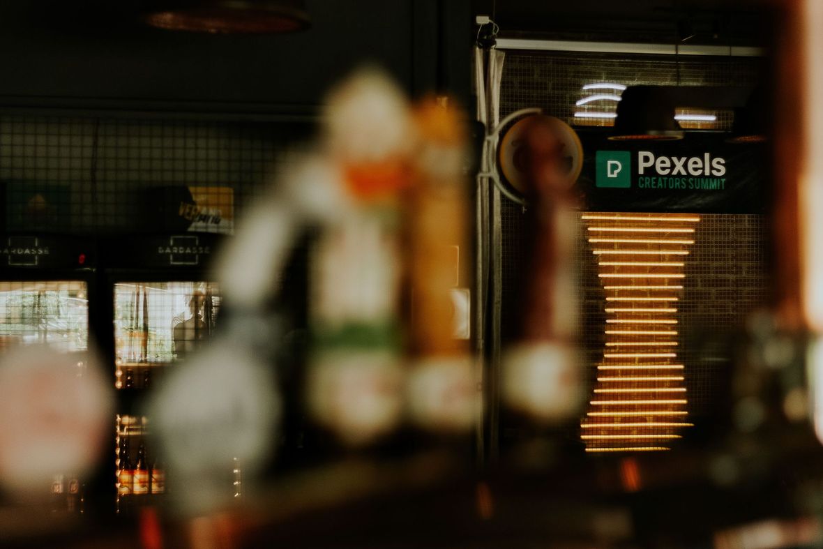 Bancone del bar sfocato con bottiglie e luci ambrate calde in un interno buio