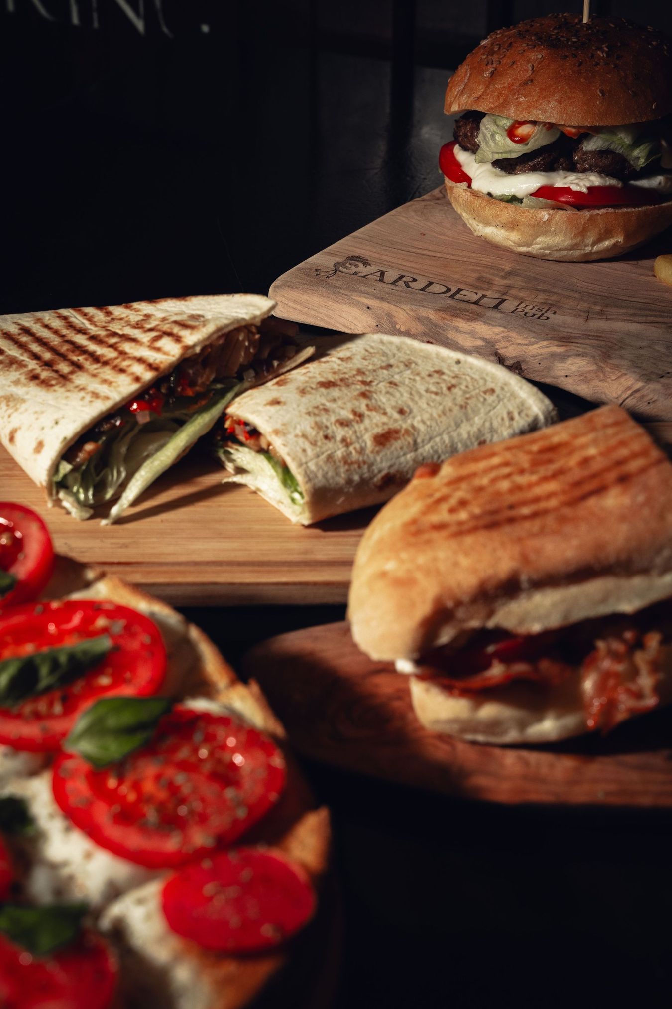 Panini assortiti e pomodori a fette su taglieri di legno, in un'atmosfera calda e rustica.