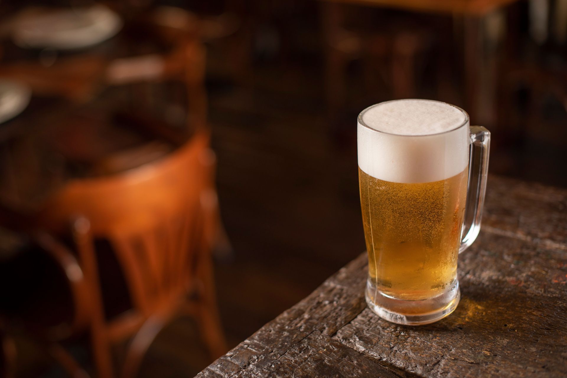 Un boccale di birra ghiacciata su un tavolo di legno in un pub scarsamente illuminato.