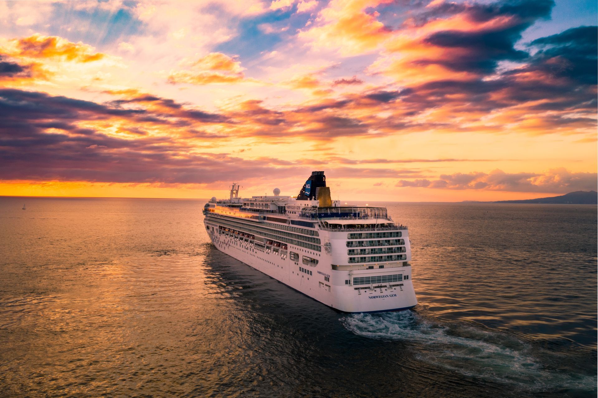 An aerial view of a cruise ship in the ocean at sunset.