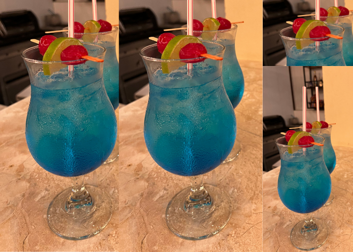 Cócteles azules adornados con cerezas y lima, sobre una encimera.