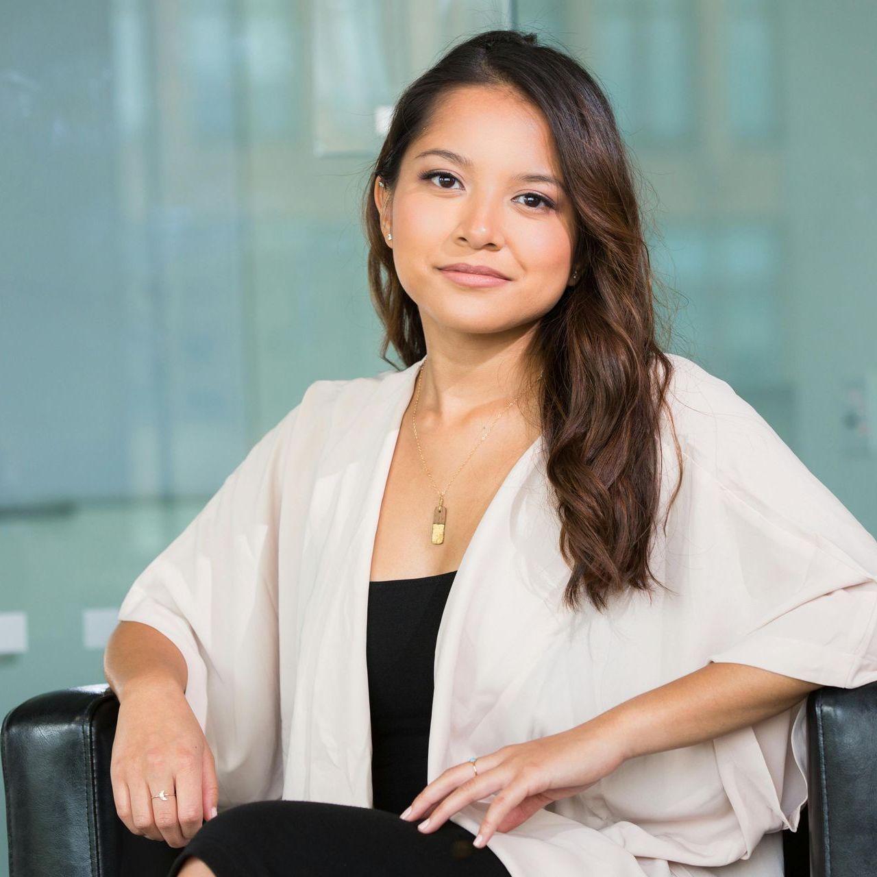 Uma mulher com um casaco branco está sentada em uma cadeira