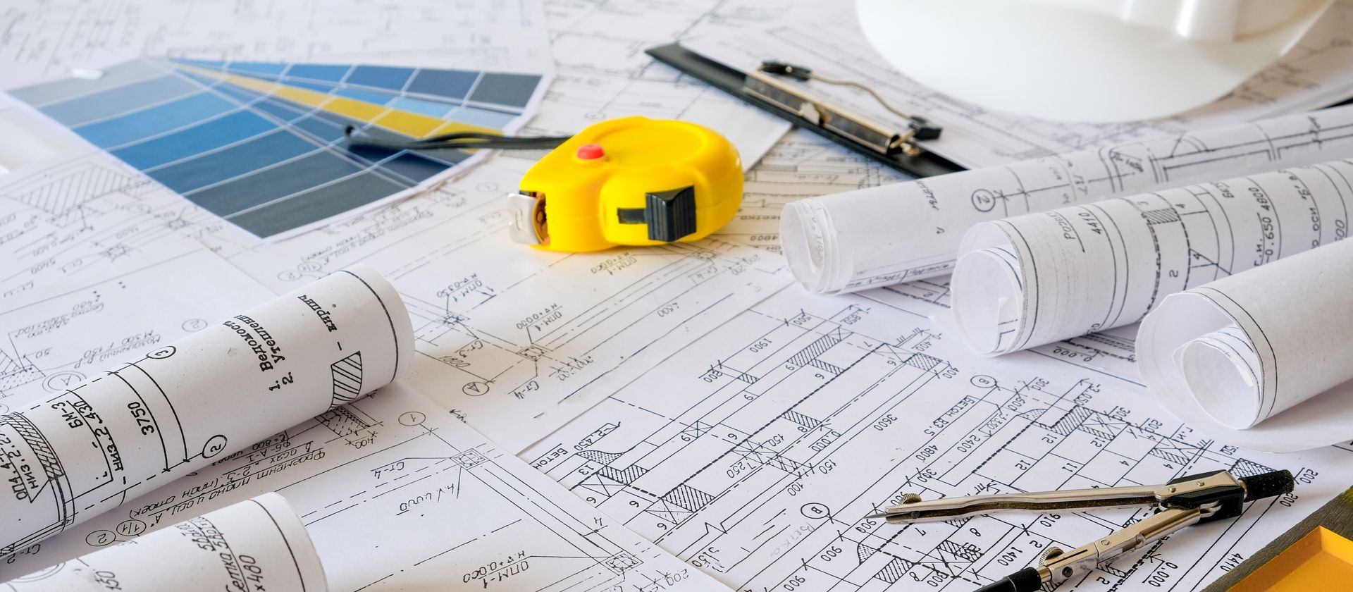 A yellow tape measure is sitting on top of a pile of blueprints.