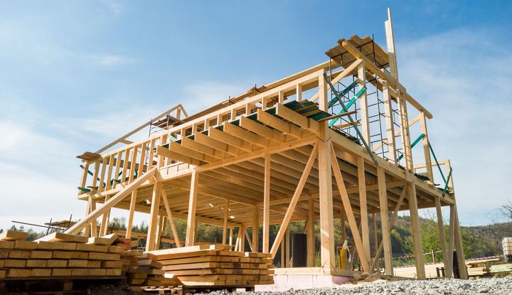A large wooden structure is being built on a sunny day.