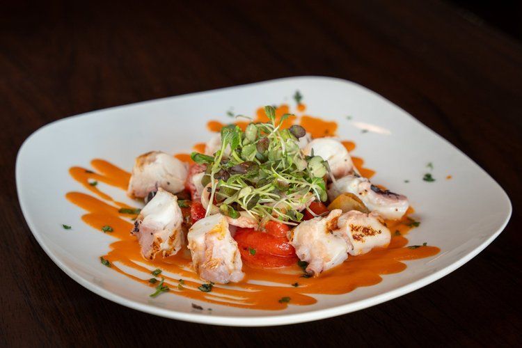 A white plate topped with shrimp and tomatoes on a wooden table.