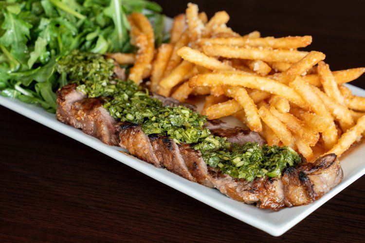 A white plate topped with steak and french fries on a table.