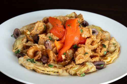 A white plate topped with chicken , peppers and olives.