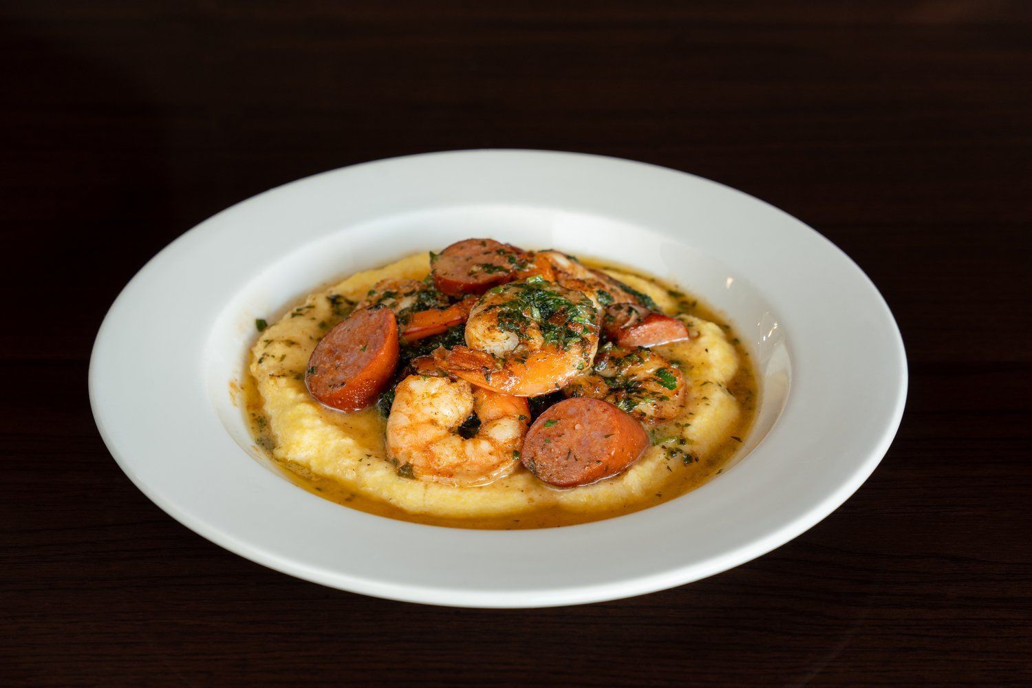 A white plate topped with shrimp and sausage on a table.