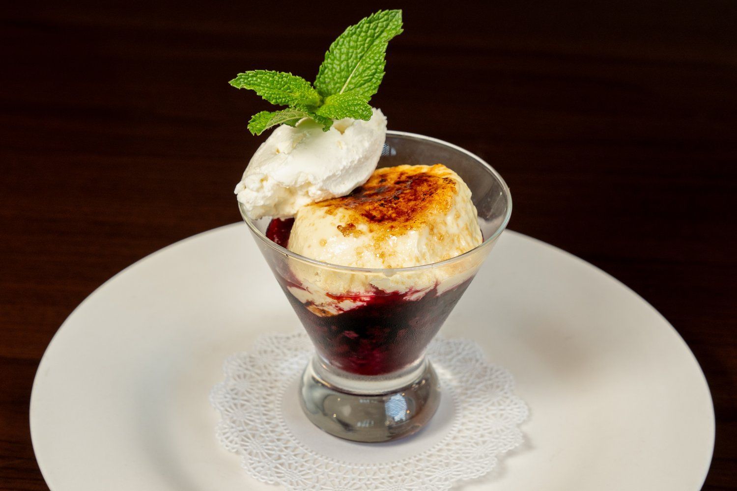 A dessert in a martini glass on a white plate.