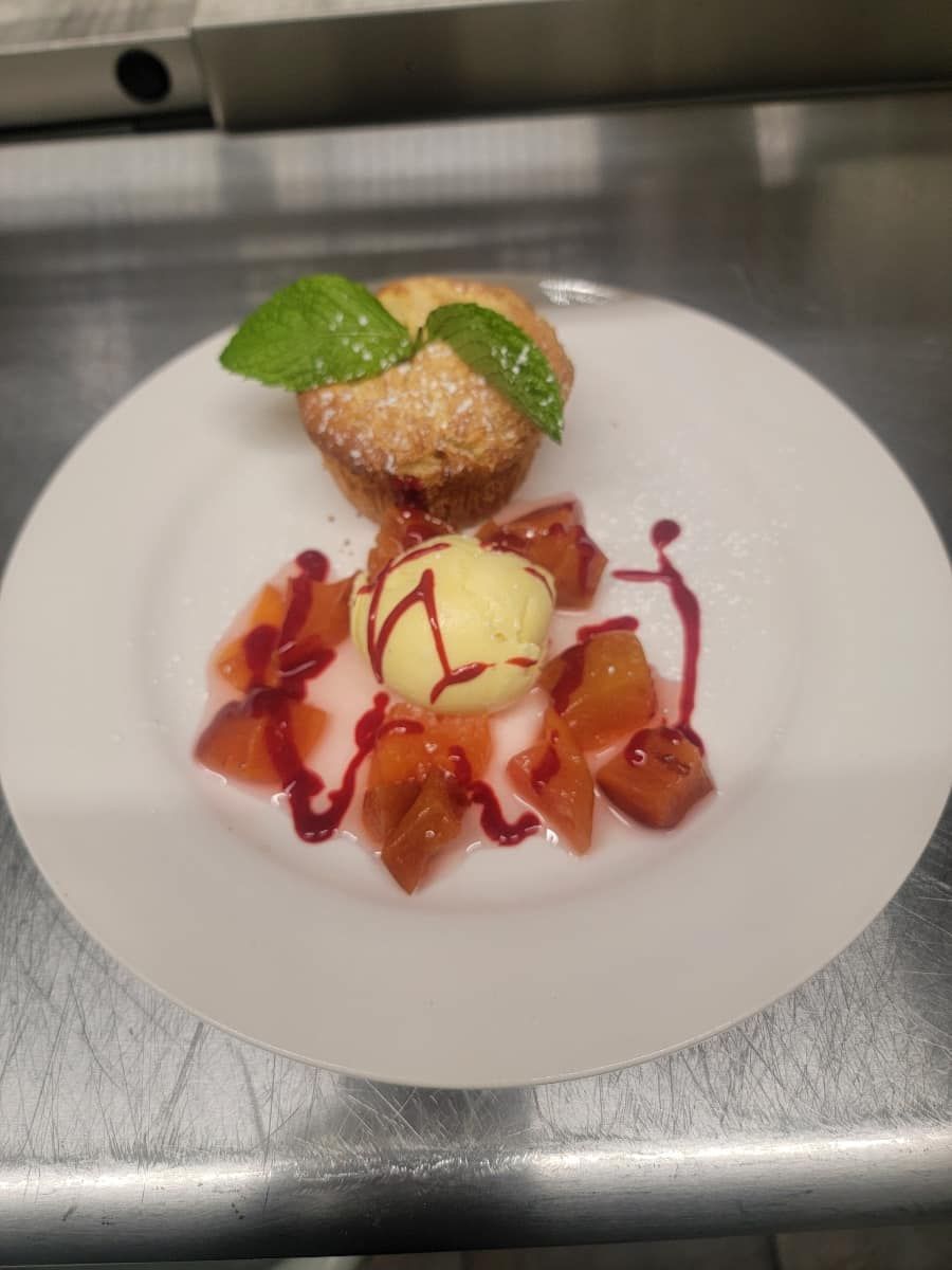 A white plate topped with a dessert with ice cream and fruit.