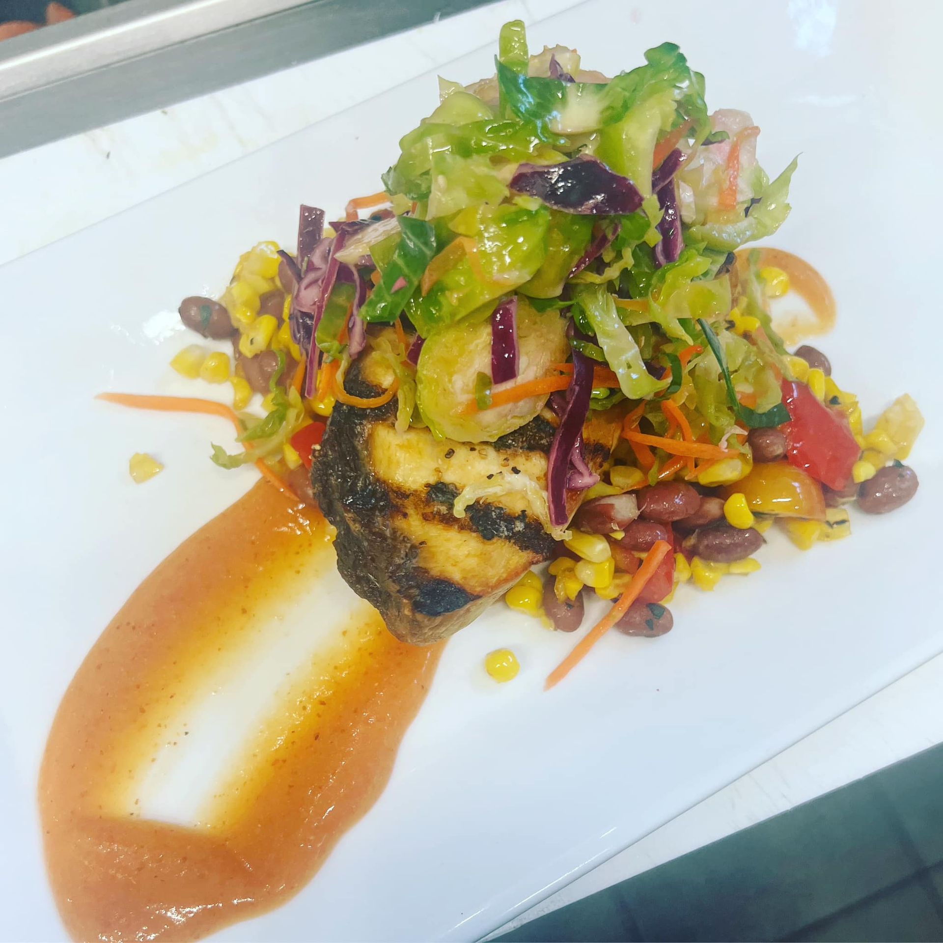 A white plate topped with a salad and a piece of meat