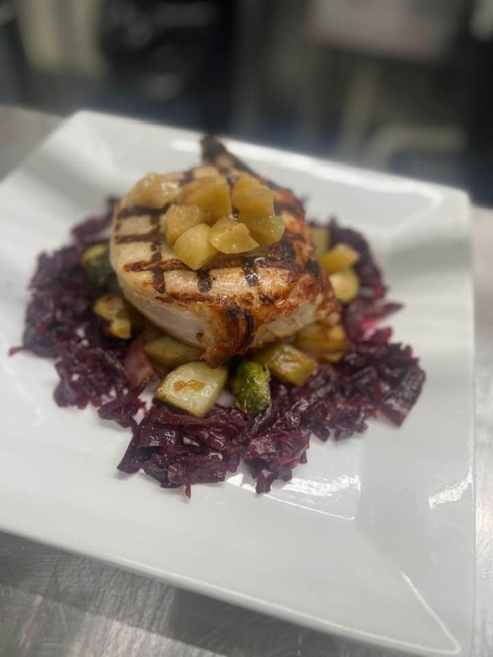 A white plate topped with meat and vegetables on a table.