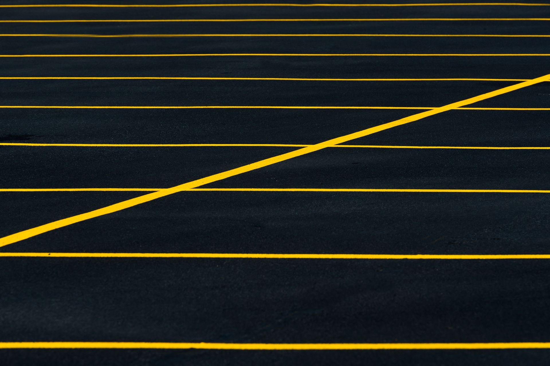 Dark asphalt with bright yellow lane markings and a diagonal stripe across the frame