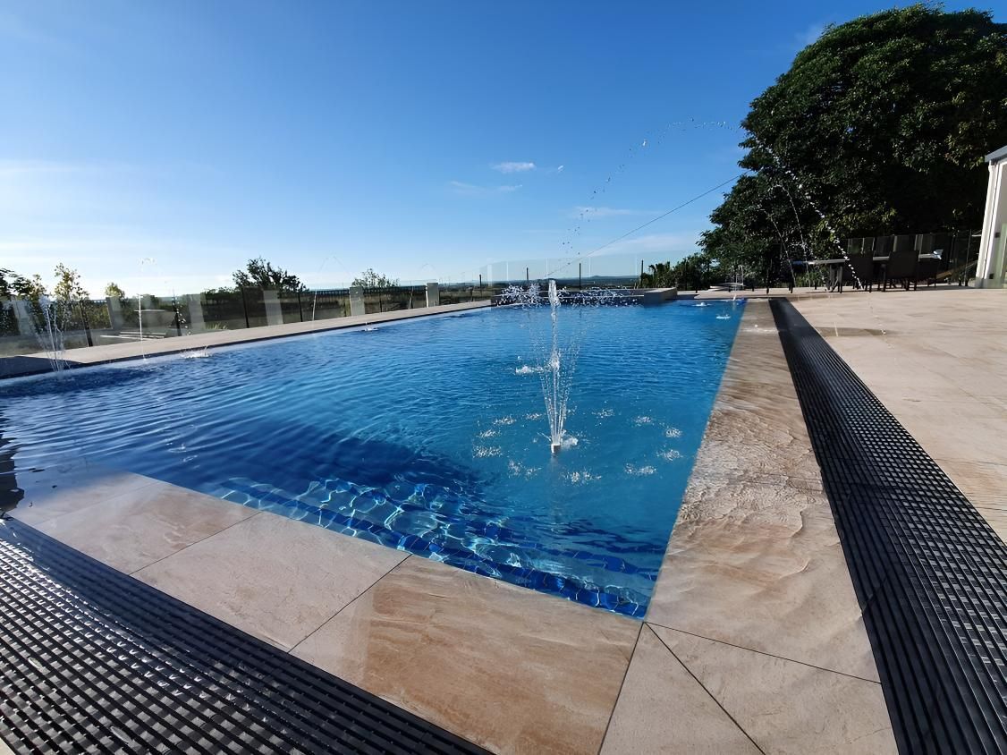 A Large Swimming Pool With A Fountain In The Middle — Doug Allen Pools In Beaconsfield, QLD