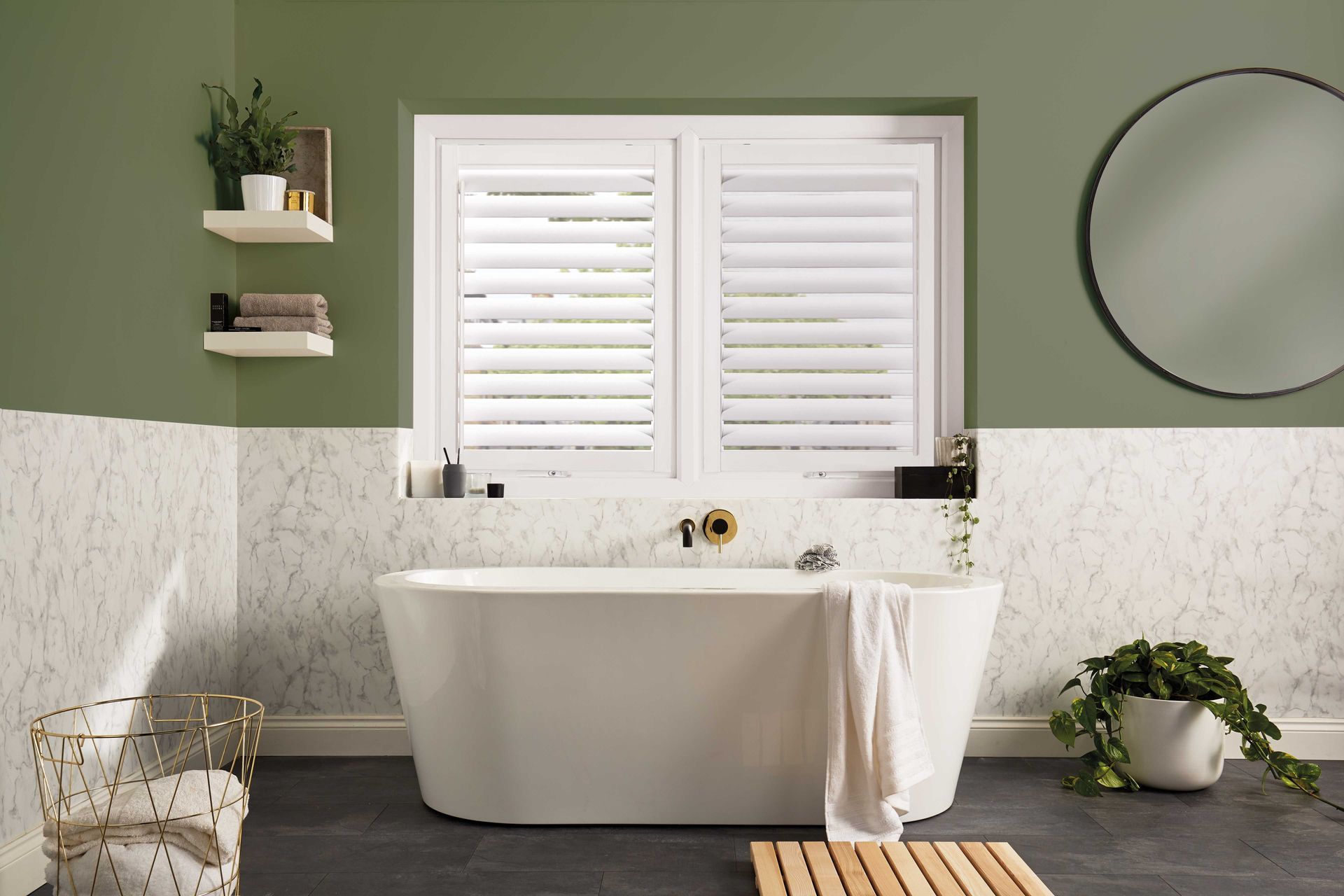 a bathroom with a bathtub , mirror , and shutters on the window .