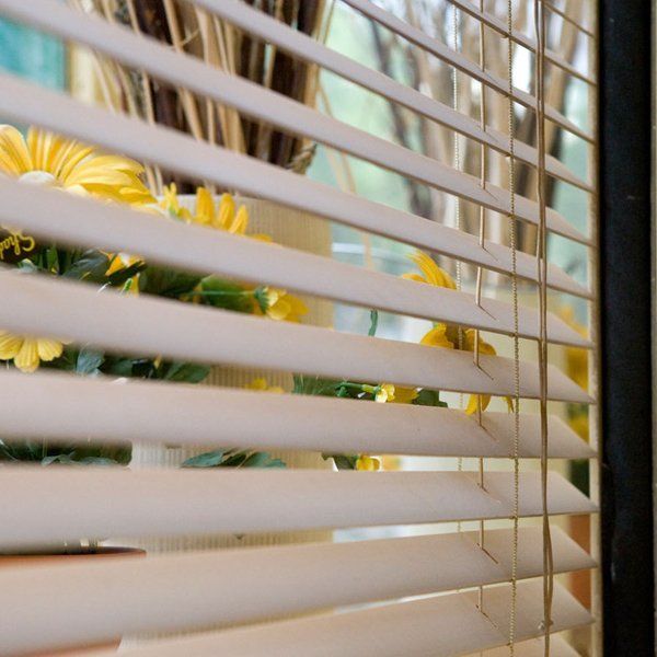 daffodils visible on a windowsill behind semi closed venetian blinds