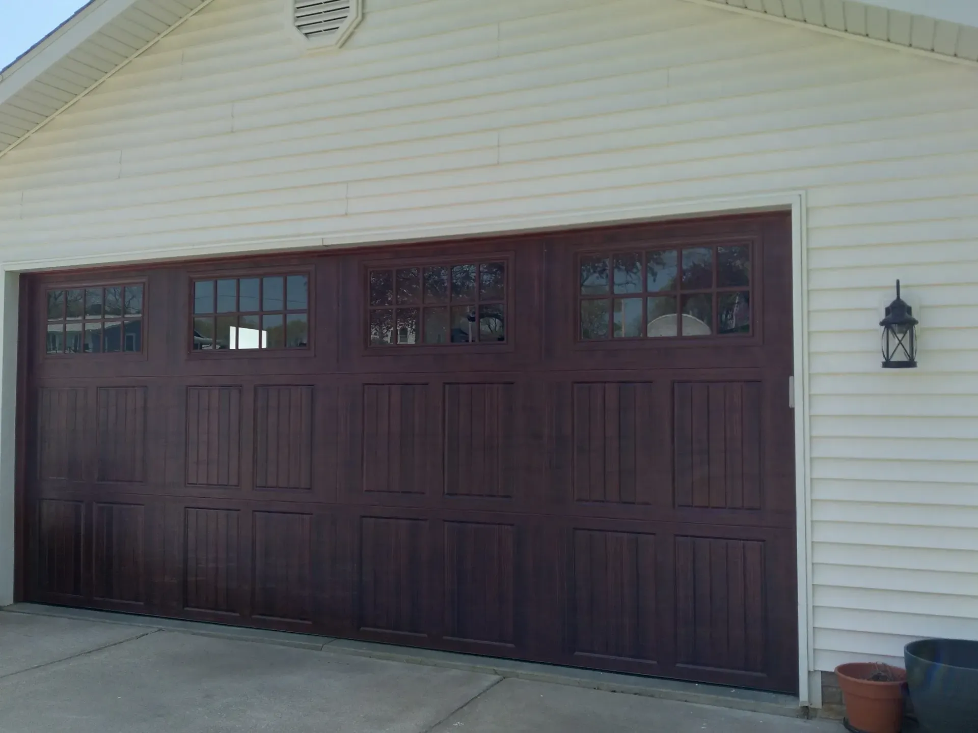 Dark brown garage door with windows and white siding.