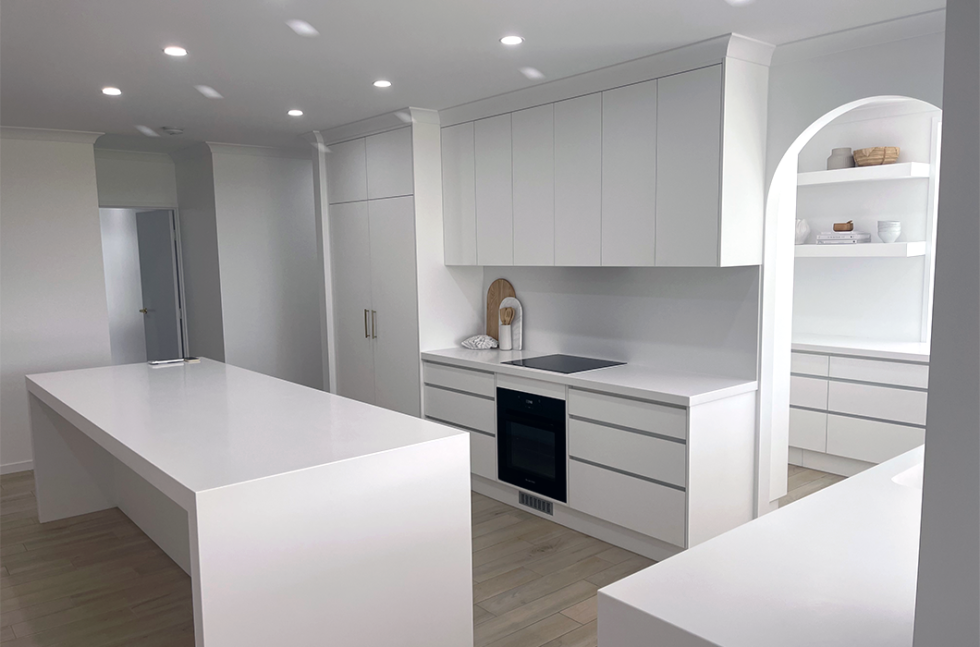 Bright modern white kitchen with island, built-in cabinets, and recessed ceiling lights