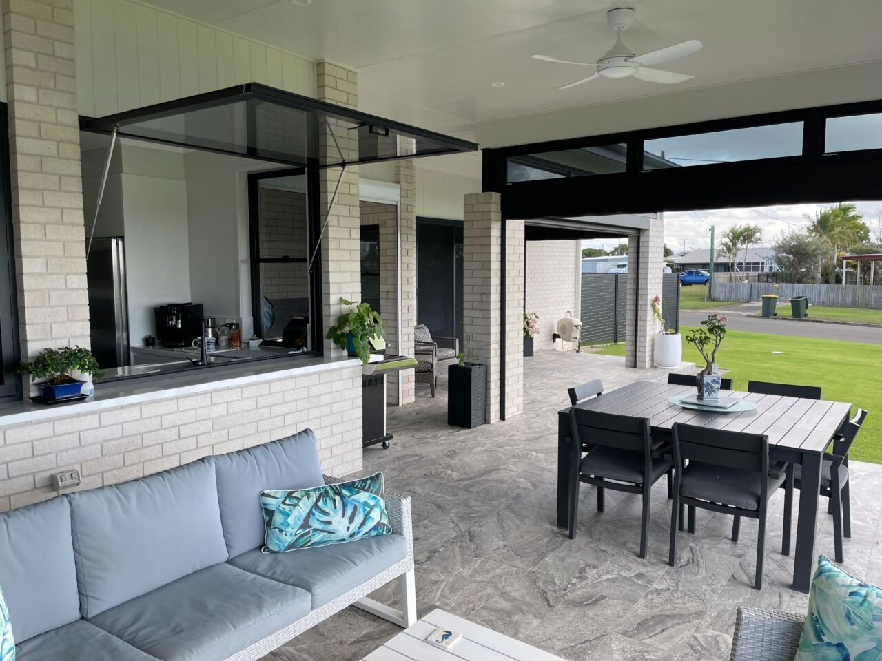 Covered patio with outdoor seating, dining table, and a view of the backyard and pool area.
