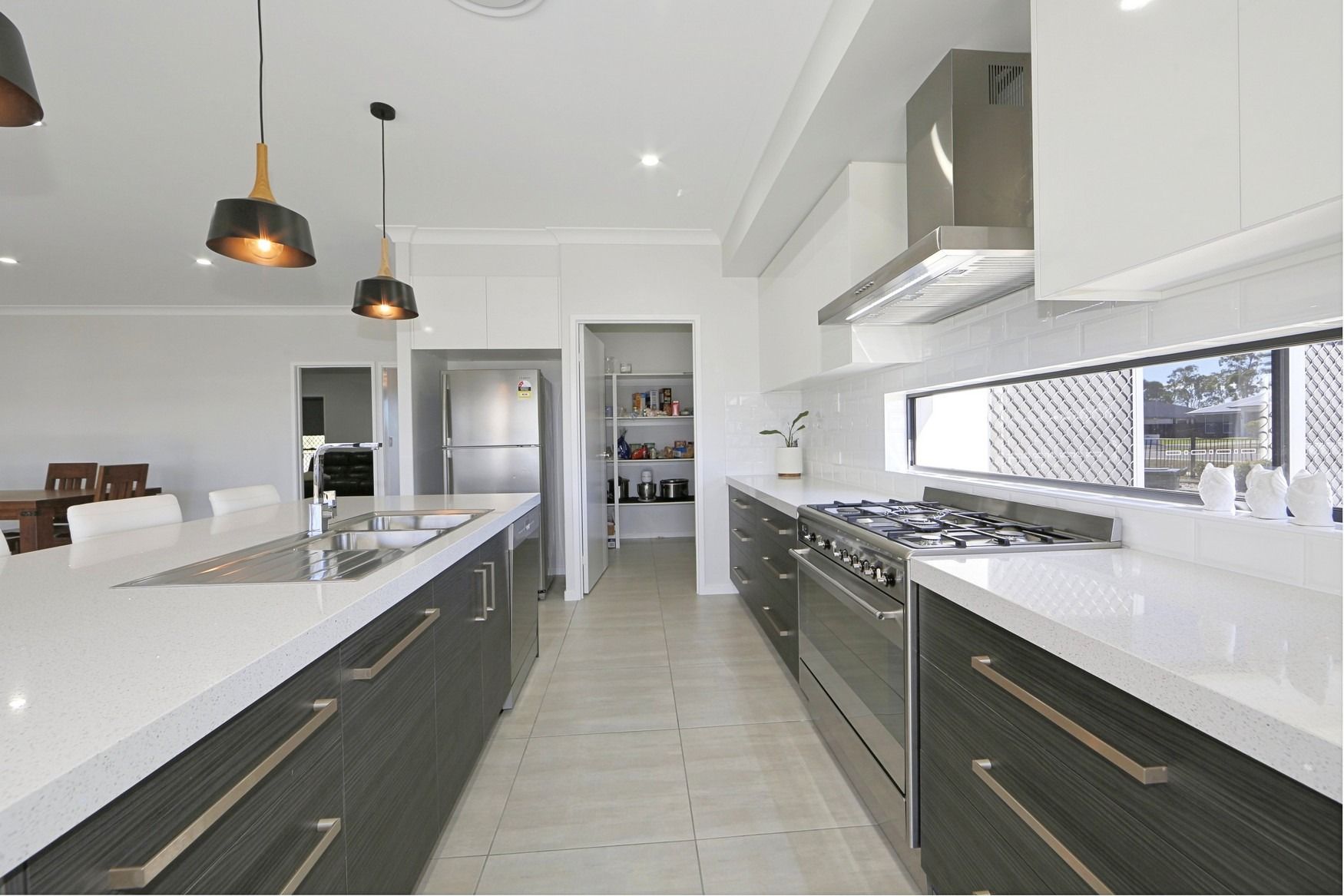 Modern white kitchen with island, stainless steel appliances, and pendant lights