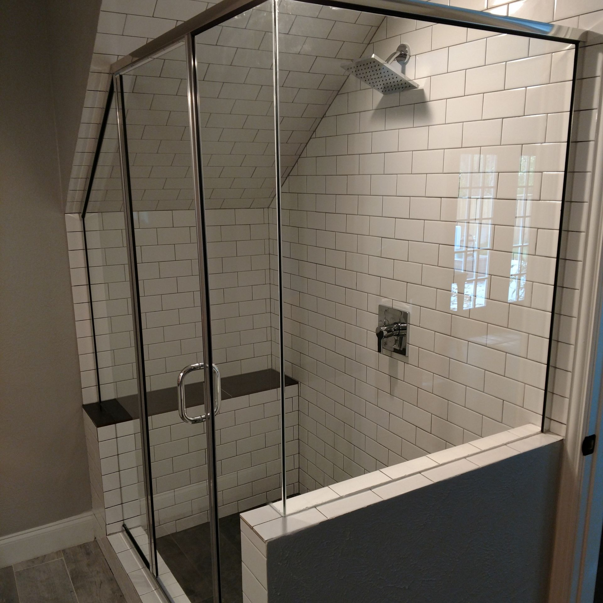 Shower with glass doors and white subway tiles; silver fixtures.