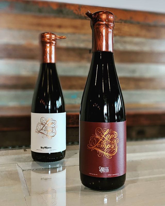two beer bottles on a wooden table at White Rooster