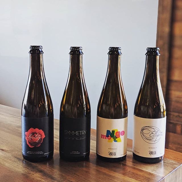four beer bottles on a White Rooster wooden table