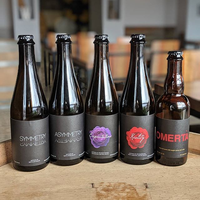 five beer bottles on a wooden barrel at White Rooster