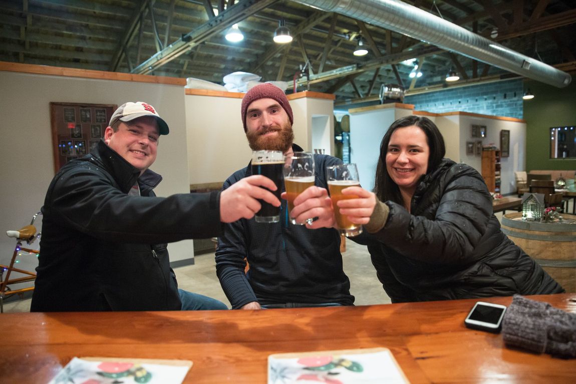 three people cheers beer glasses at White Rooster Tasting Room