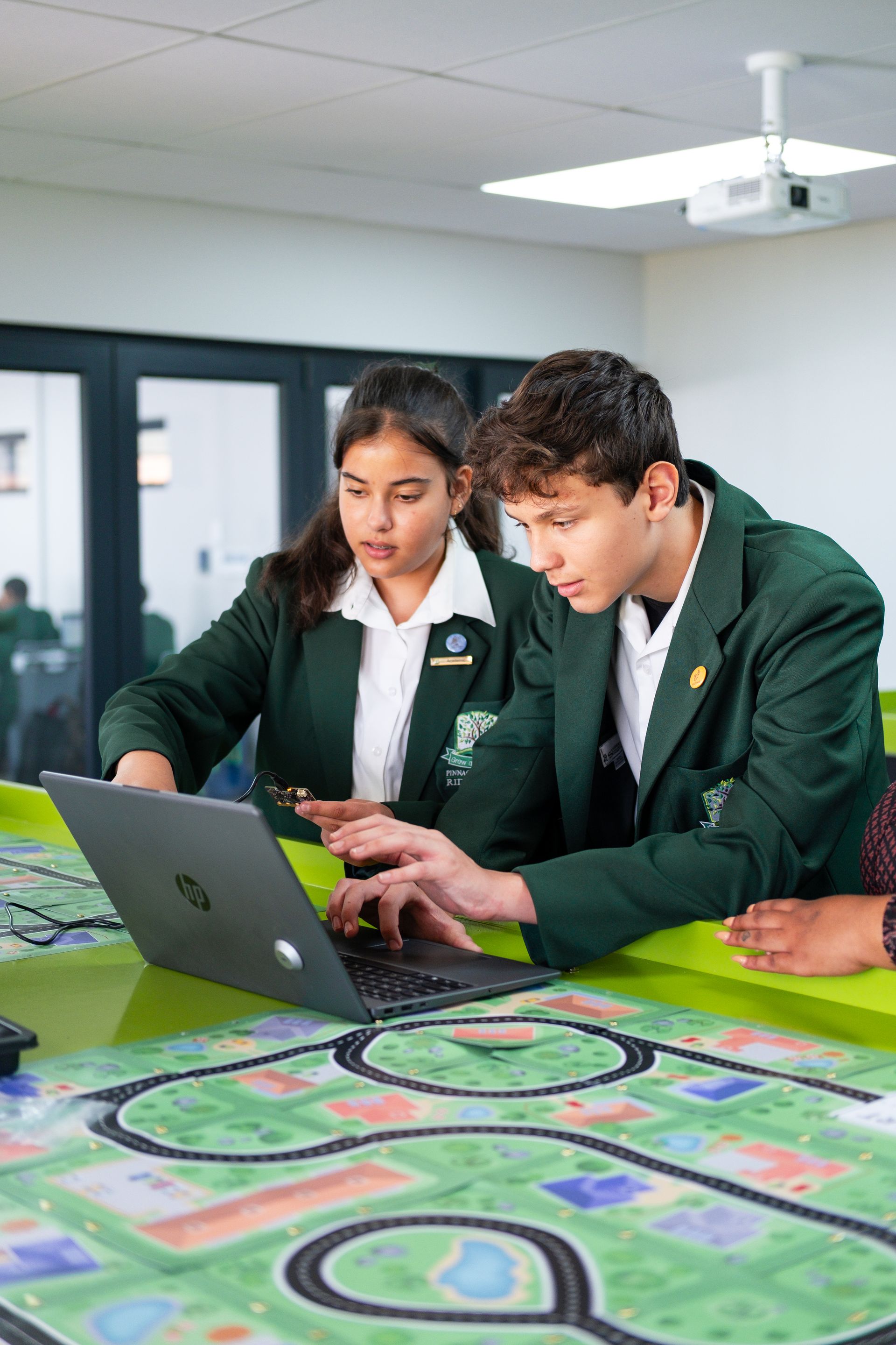 A woman in a green jacket is looking through a microscope.
