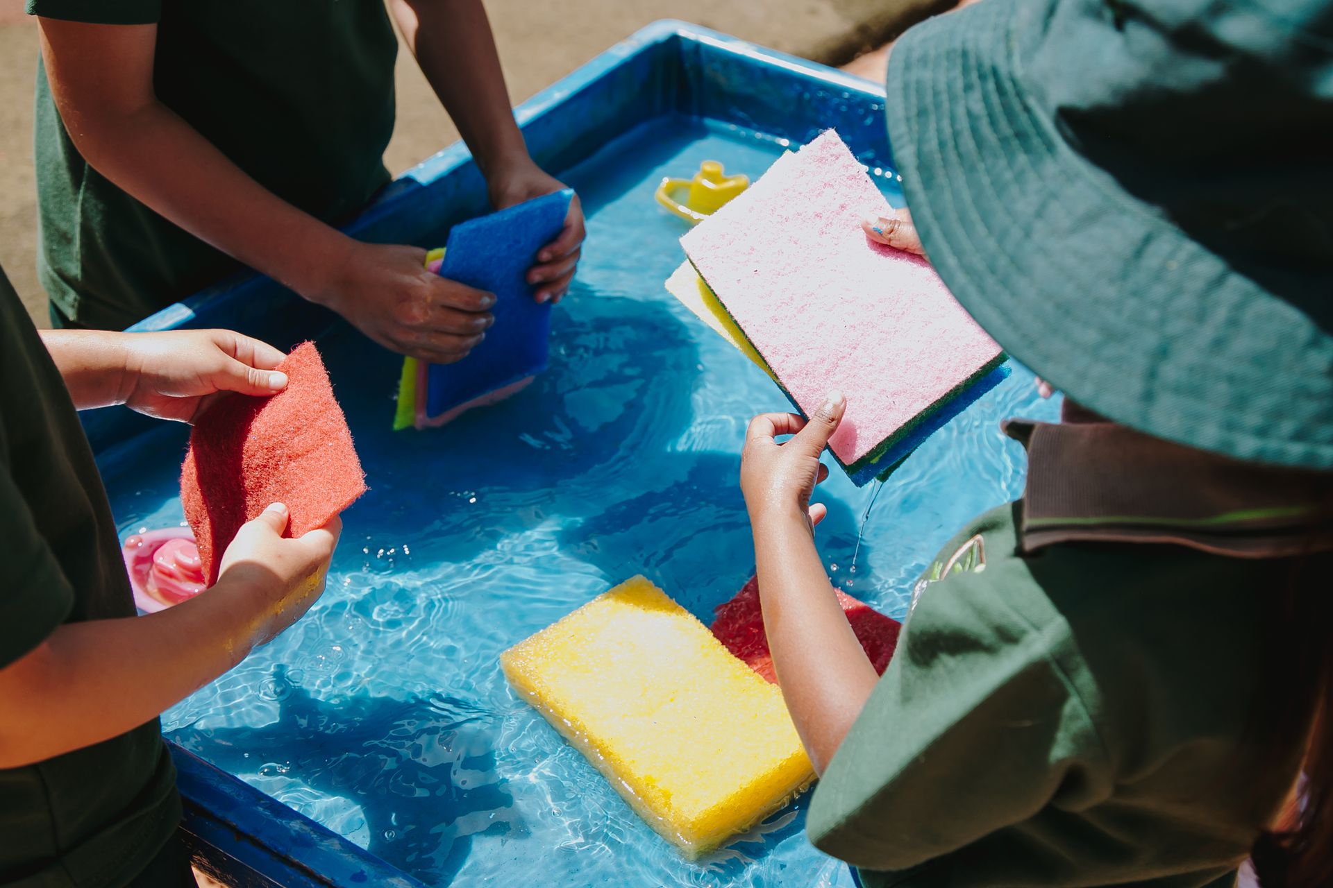 A group of children are playing with sponges in a water table.