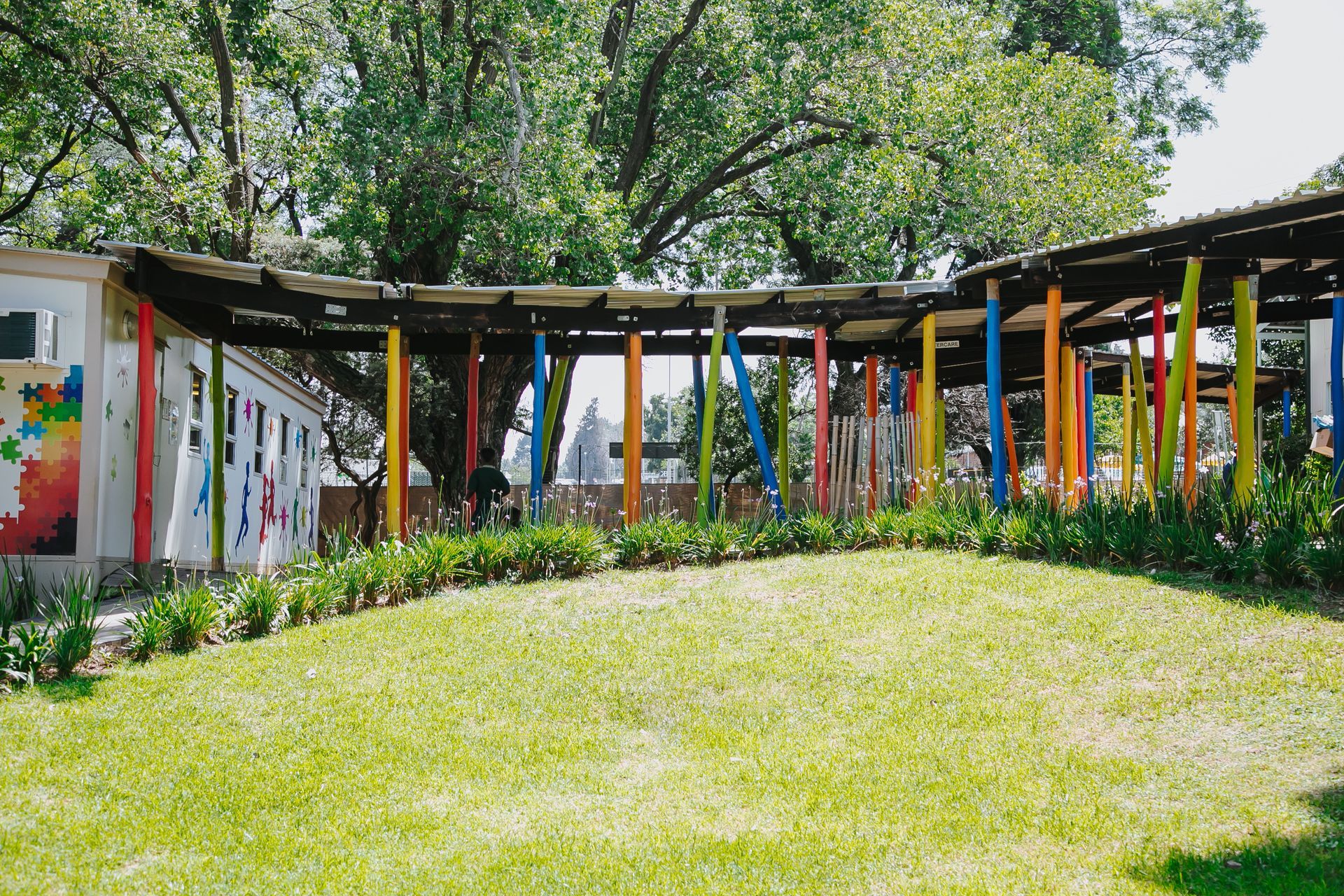 A row of colorful pillars surround a lush green field.