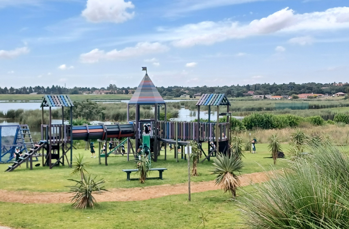 A playground in a park with a lake in the background.