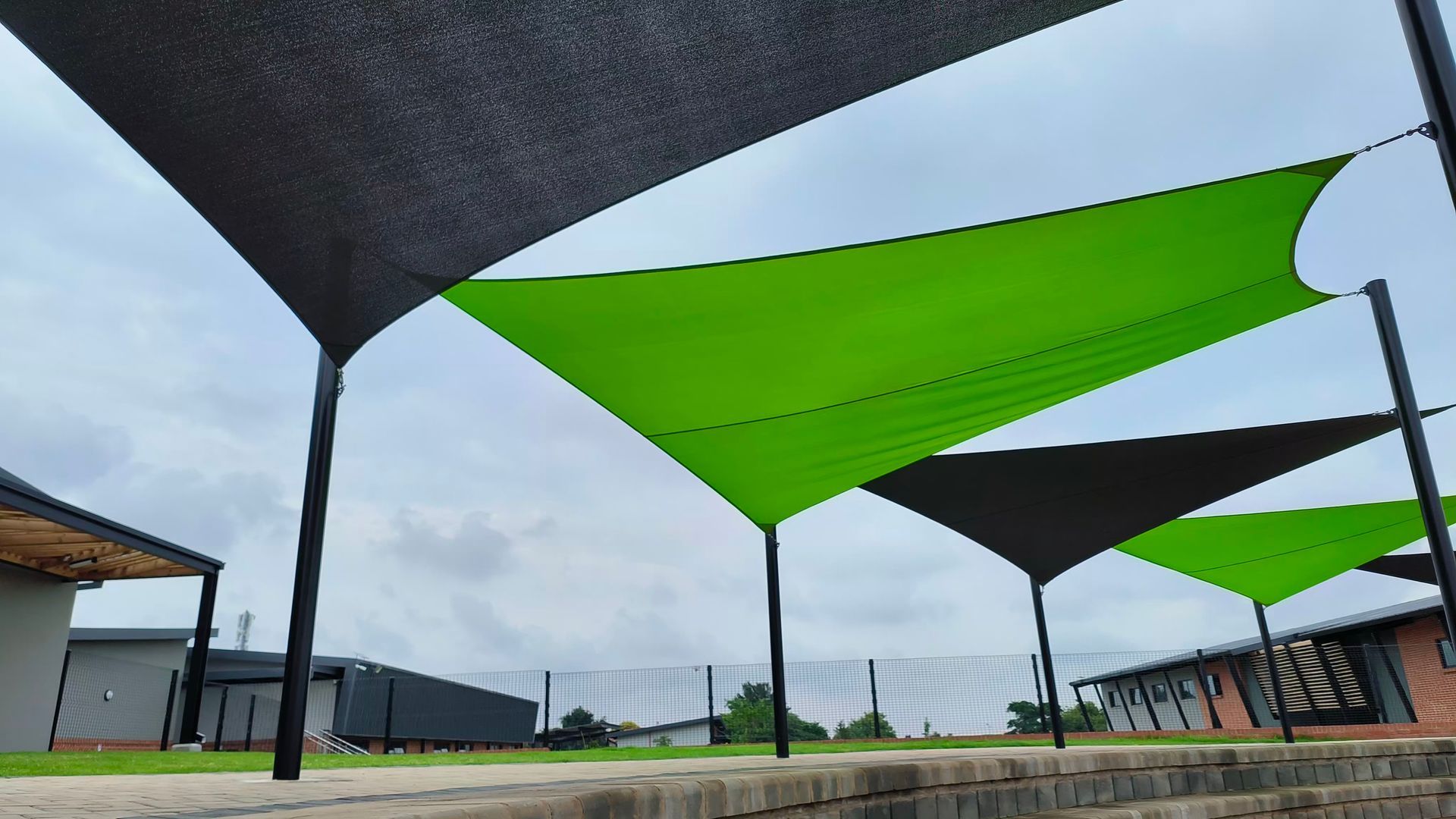 A row of green and black umbrellas are sitting on top of a brick wall.