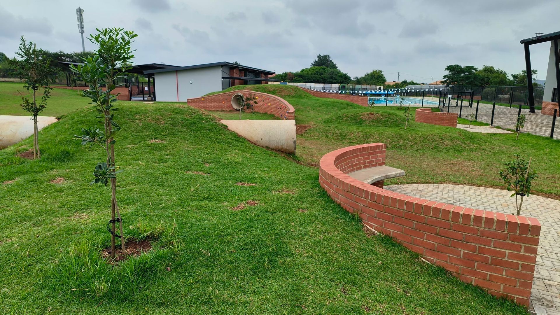 A brick wall is surrounded by grass and trees in a park.