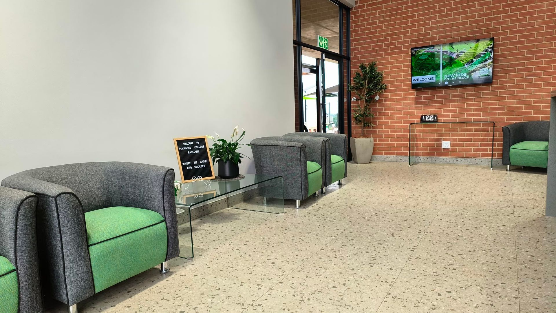 A waiting room with green chairs and a television on the wall.
