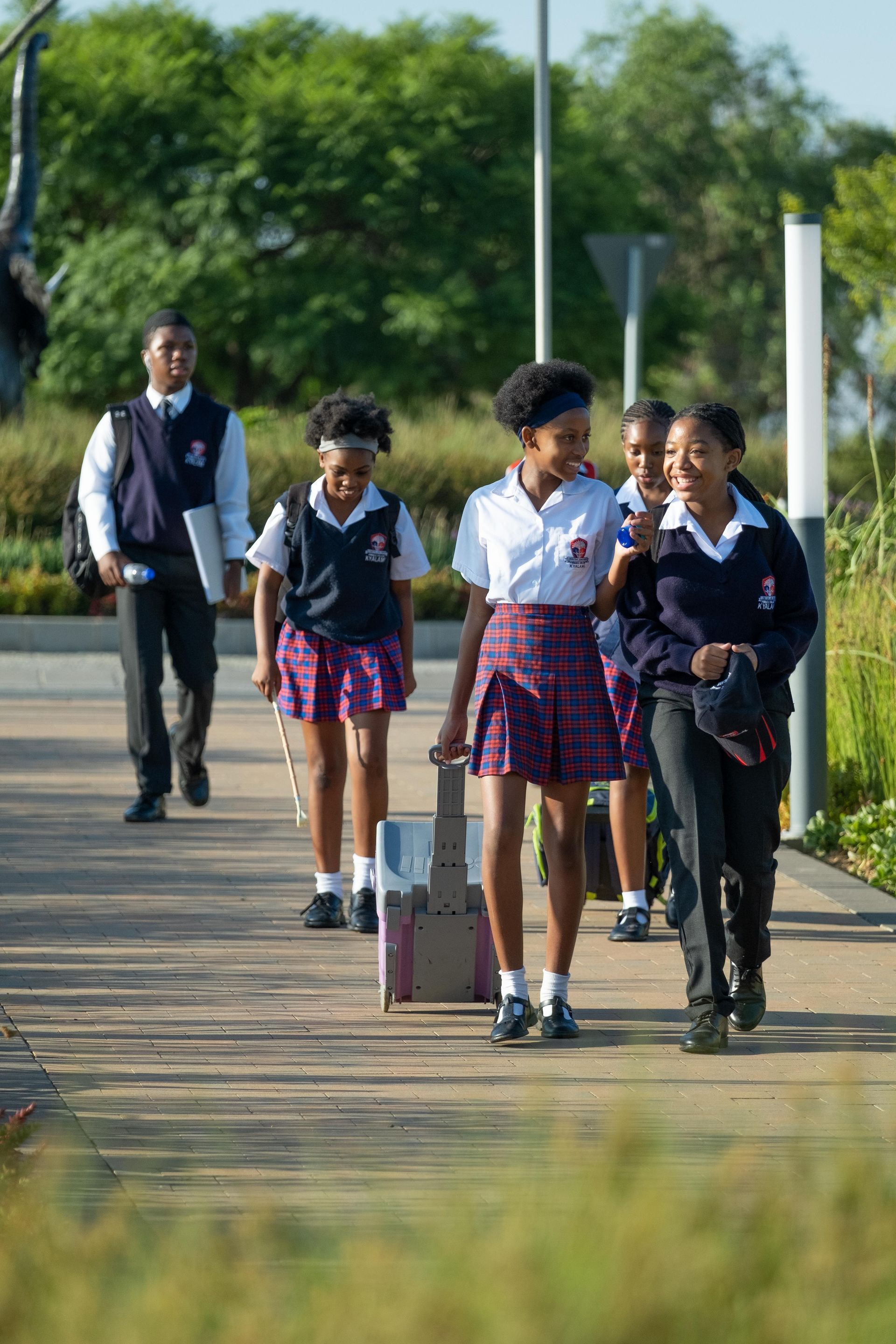 A group of children in school uniforms are walking down a sidewalk.