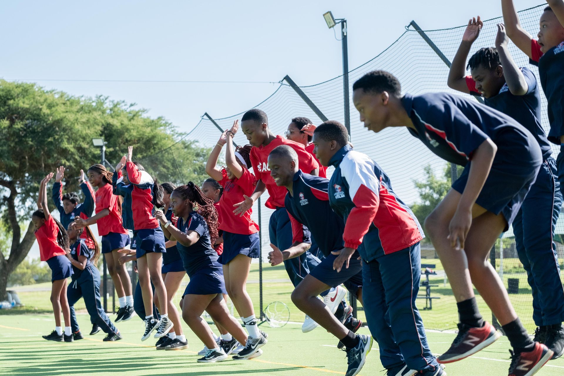 A group of children are jumping in the air on a field.