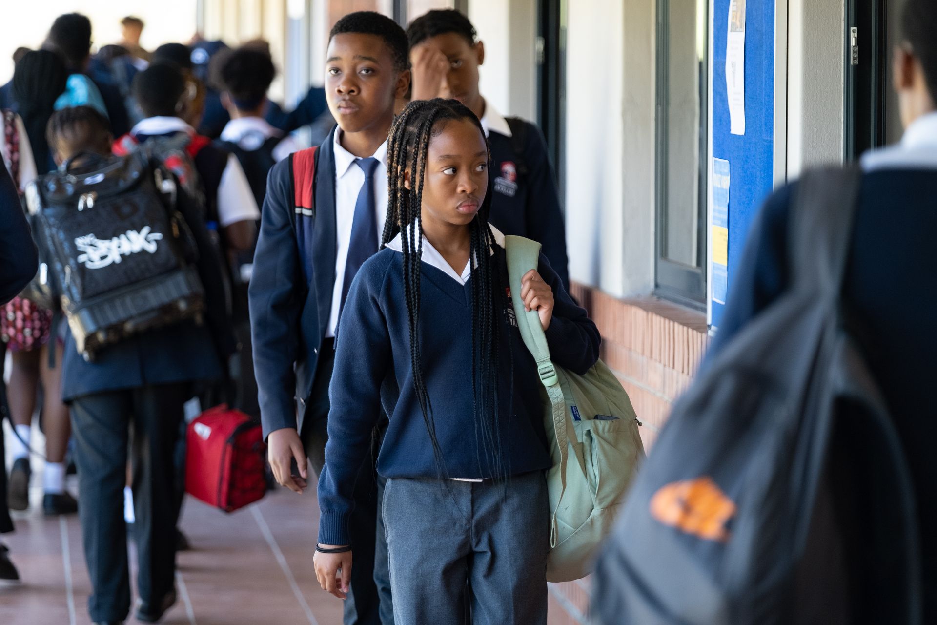 A group of children in school uniforms are walking down a hallway.
