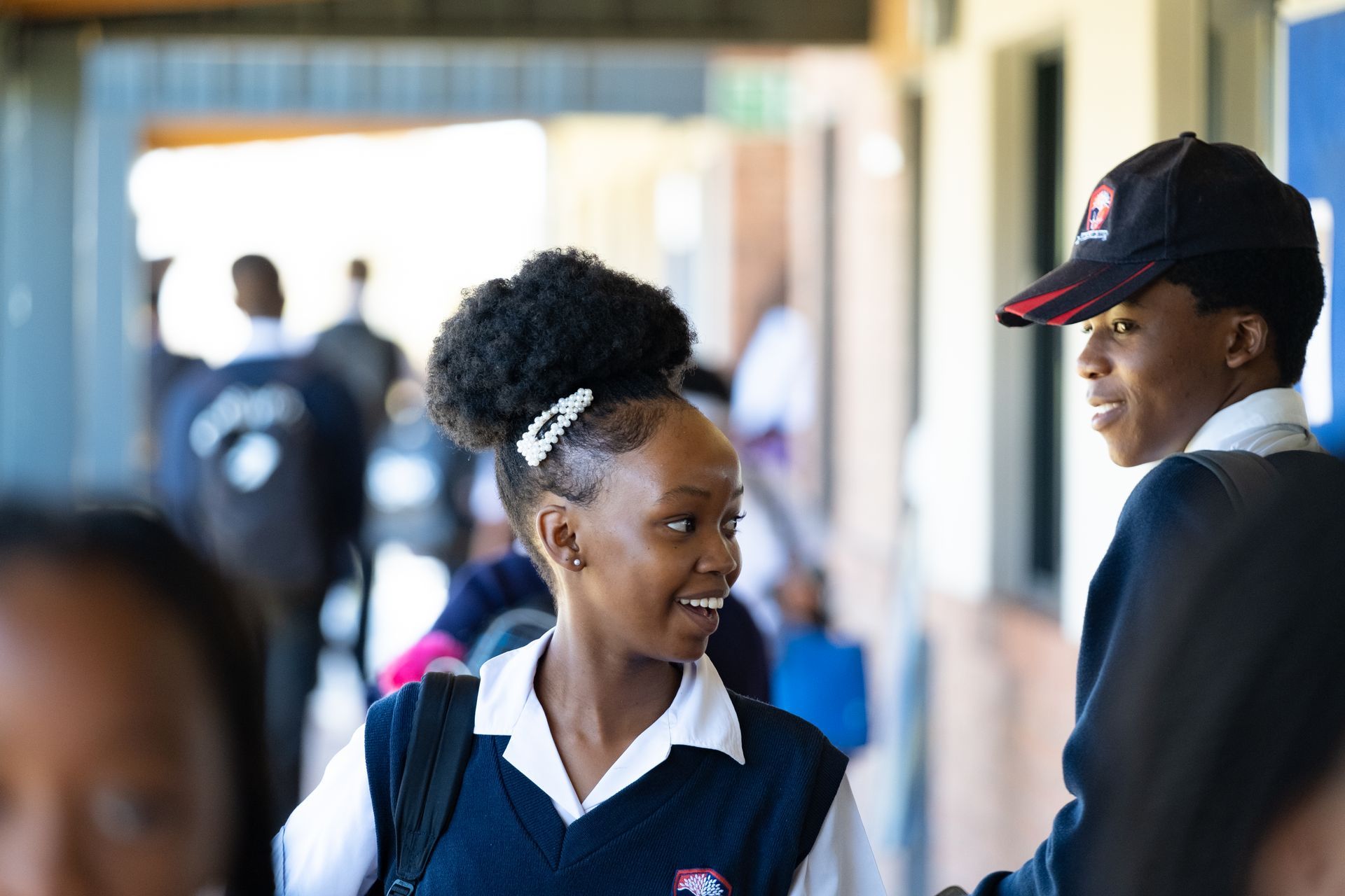 A boy and a girl are standing next to each other in a hallway.