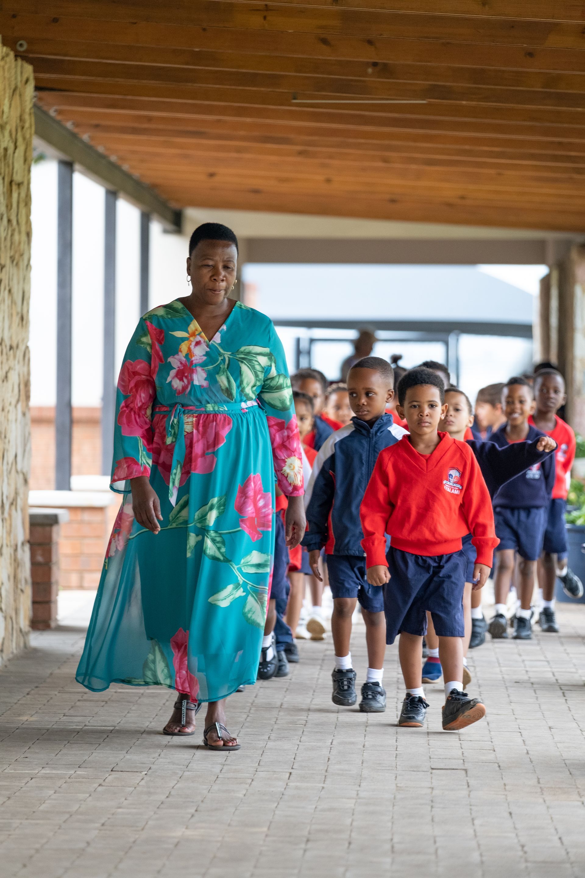 A woman is walking with a group of children on a sidewalk.