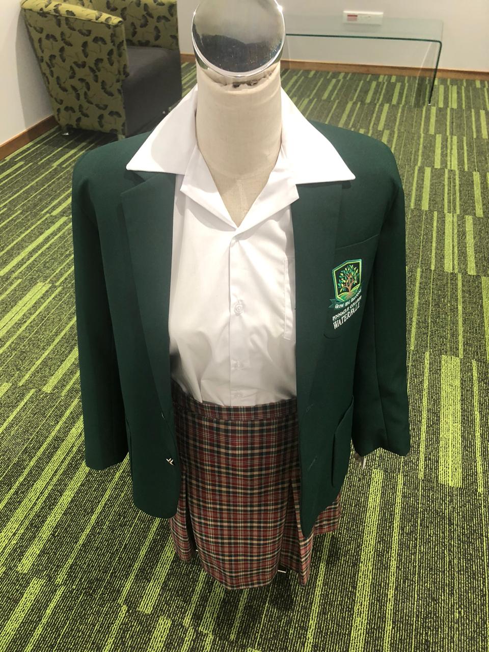 A mannequin is wearing a school uniform with a green jacket and plaid skirt.