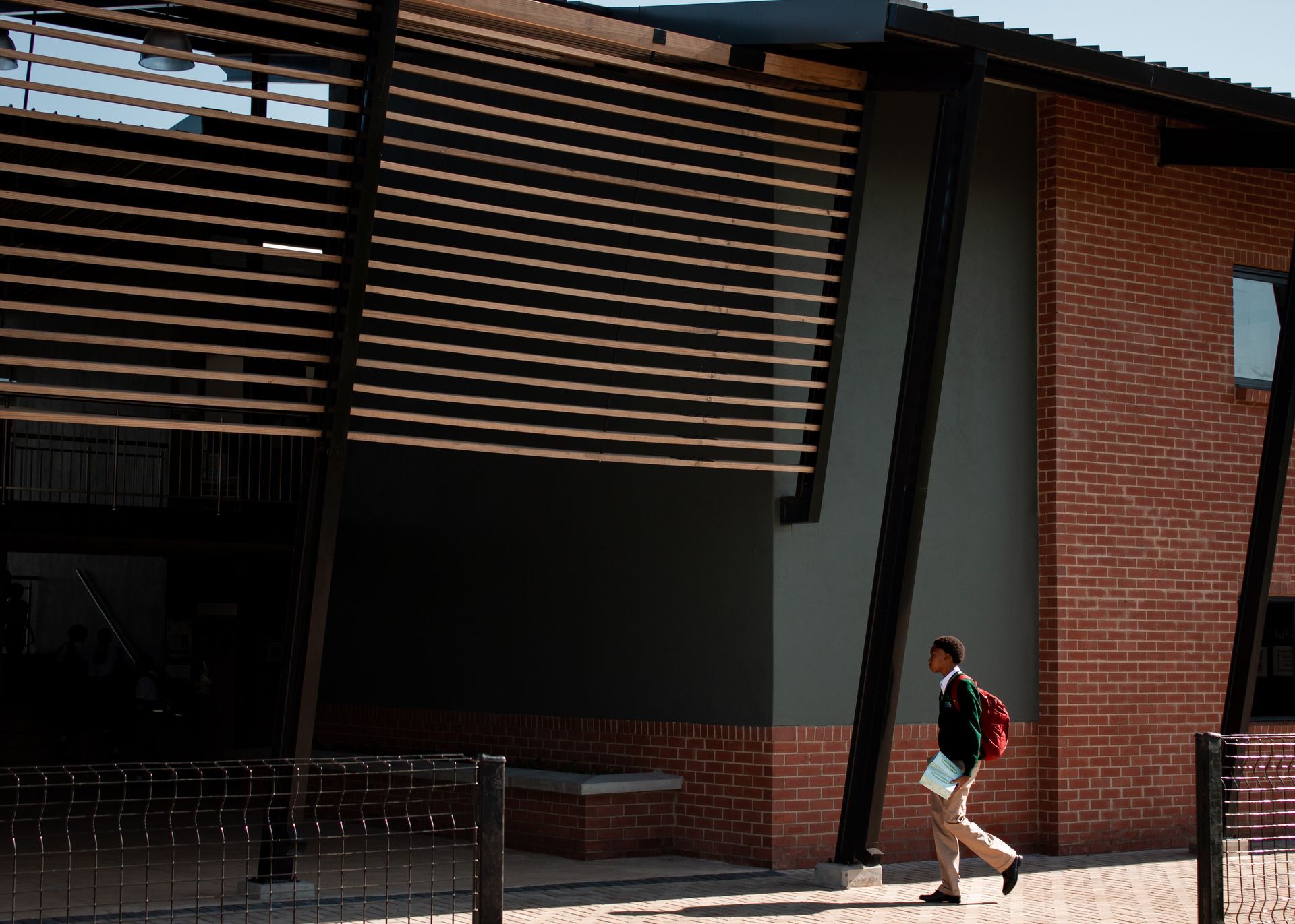 A man with a backpack is walking in front of a brick building
