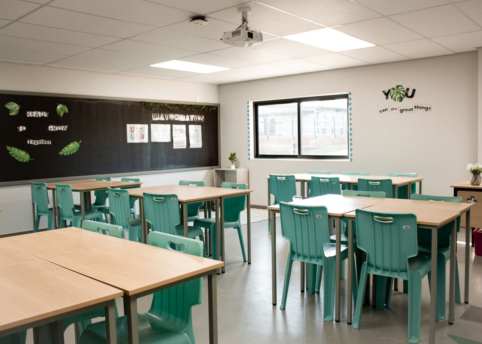A classroom with tables and chairs and a projector.