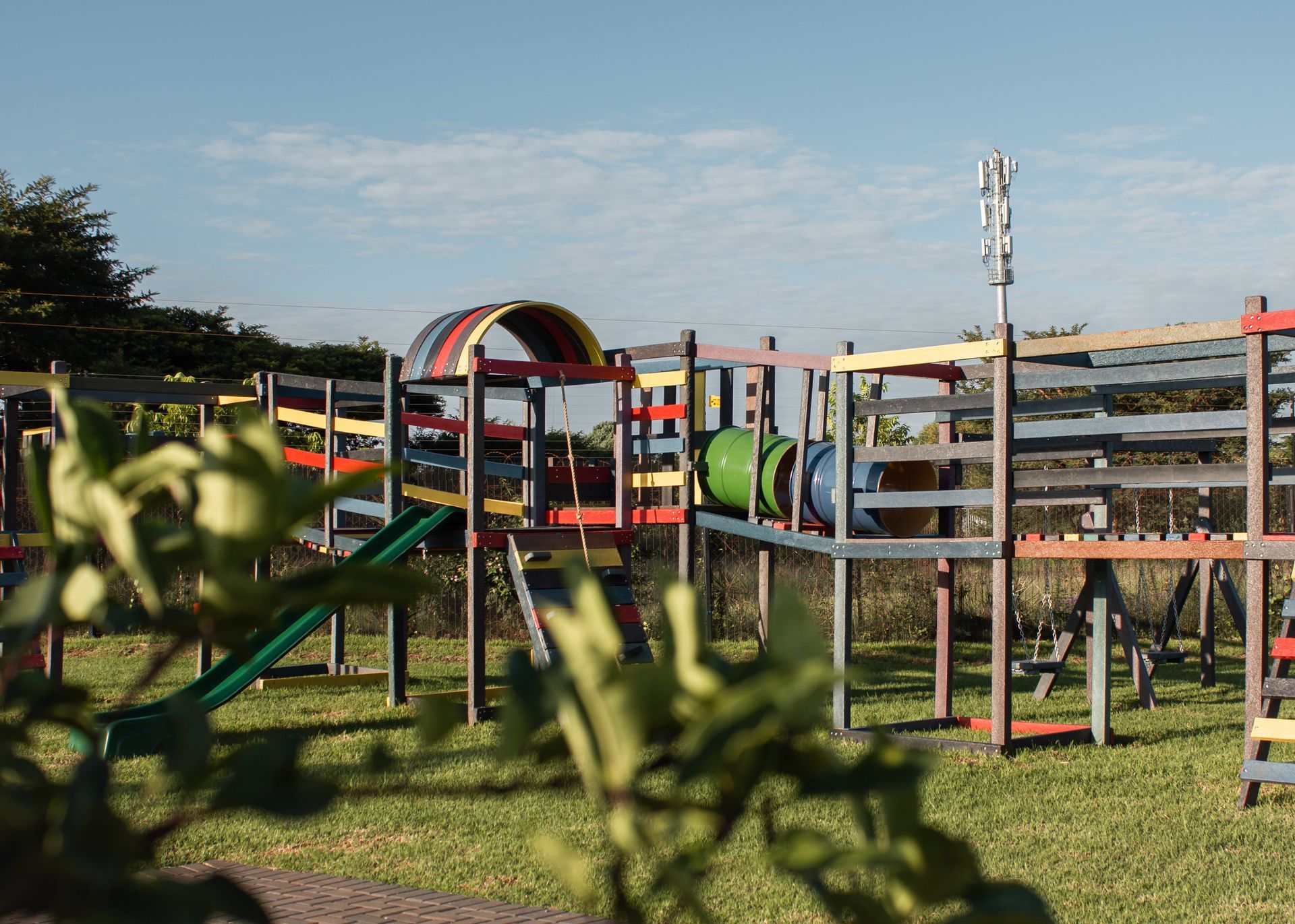 A colorful playground with a slide and a tunnel in a grassy field.
